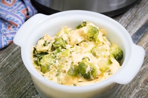 brussel sprouts with cheese sauce in white serving bowl
