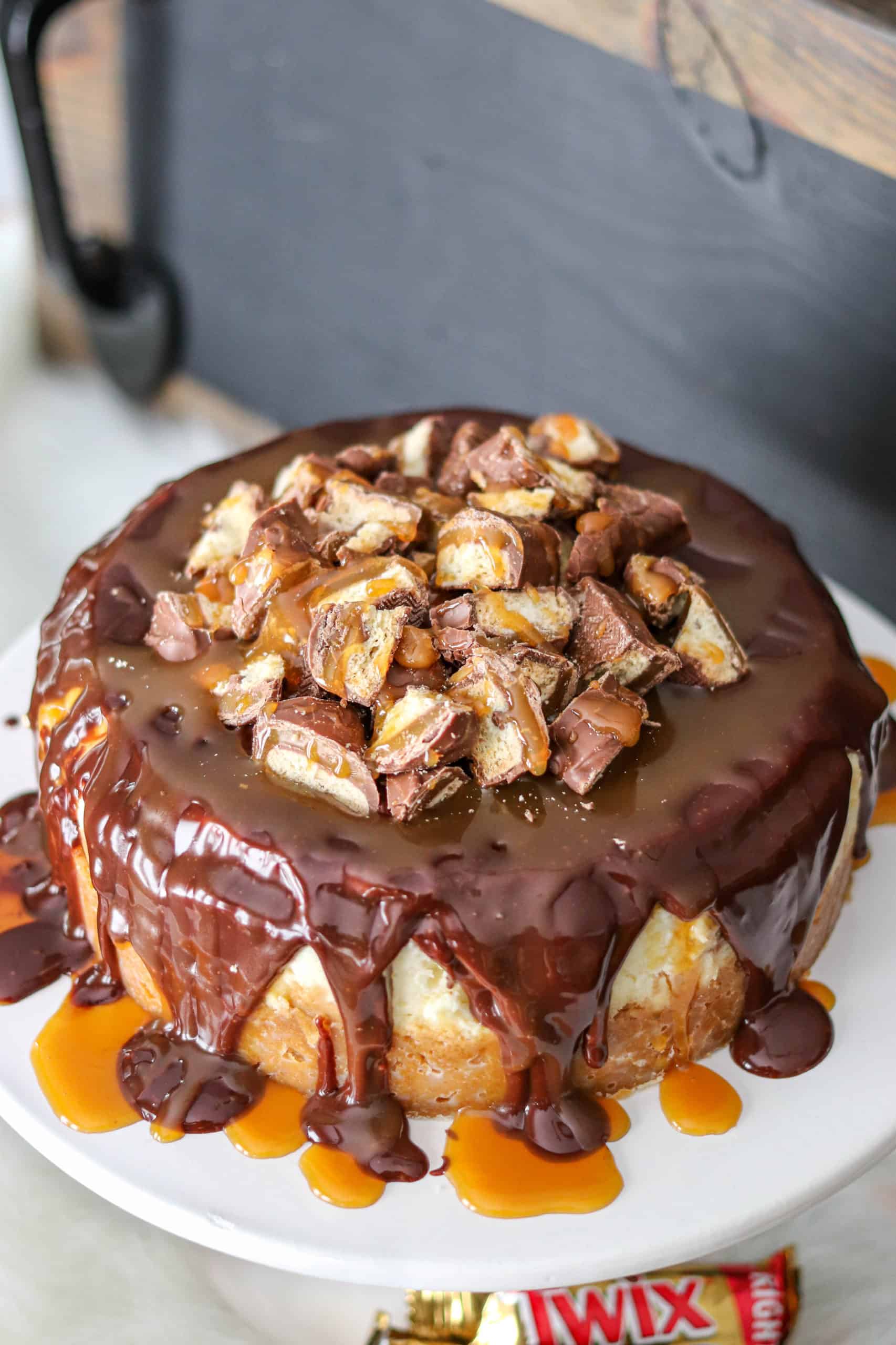 whole Instant Pot Twix Cheesecake with chocolate ganache, caramel and chopped Twix candy on top