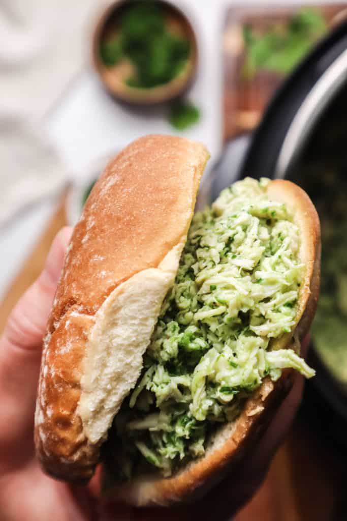 hand holding bun with chicken chimichurri in it