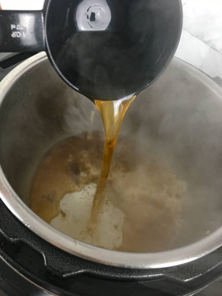 pouring in broth to deglaze pot