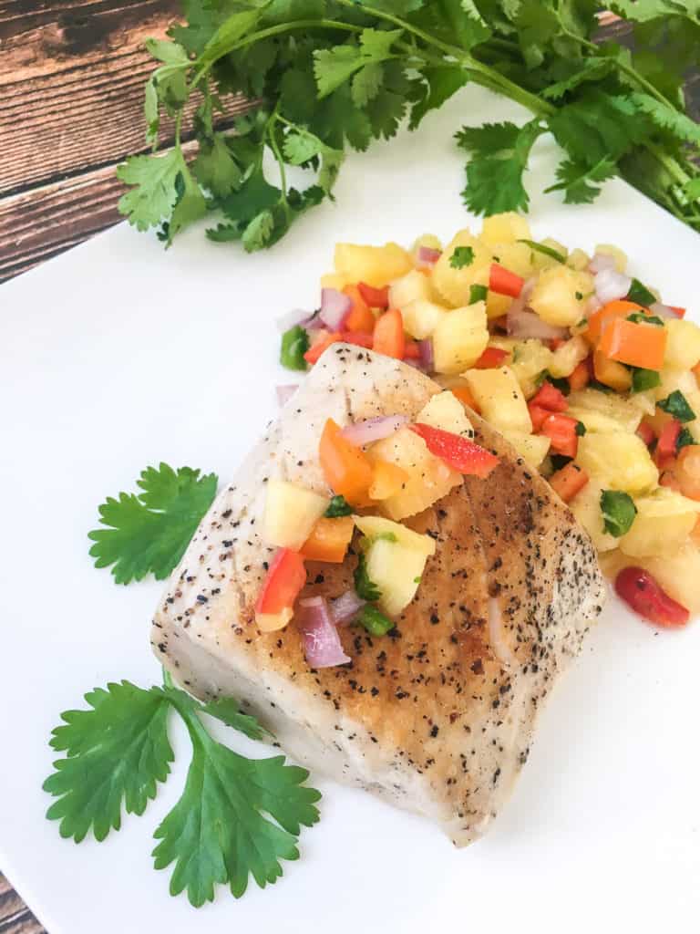 swordfish with fruit salsa on white plate