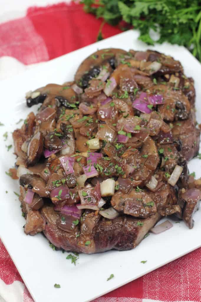 steak with mushrooms and onions on white plate